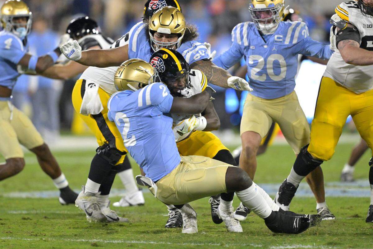 Nov 8, 2024; Pasadena, California, USA;   Iowa Hawkeyes running back Kaleb Johnson (2) is brought down by UCLA Bruins linebacker Oluwafemi Oladejo (2) for a loss of yardage in the first half at the Rose Bowl. Mandatory Credit: Jayne Kamin-Oncea-Imagn Images