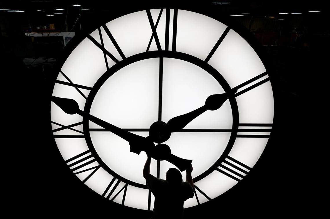 FILE - Electric Time technician Dan LaMoore puts a clock hand onto a 1000-lb., 12-foot diameter clock constructed for a resort in Vietnam, Tuesday, March 9, 2021, in Medfield, Mass. AP Photo/Elise Amendola, File)
