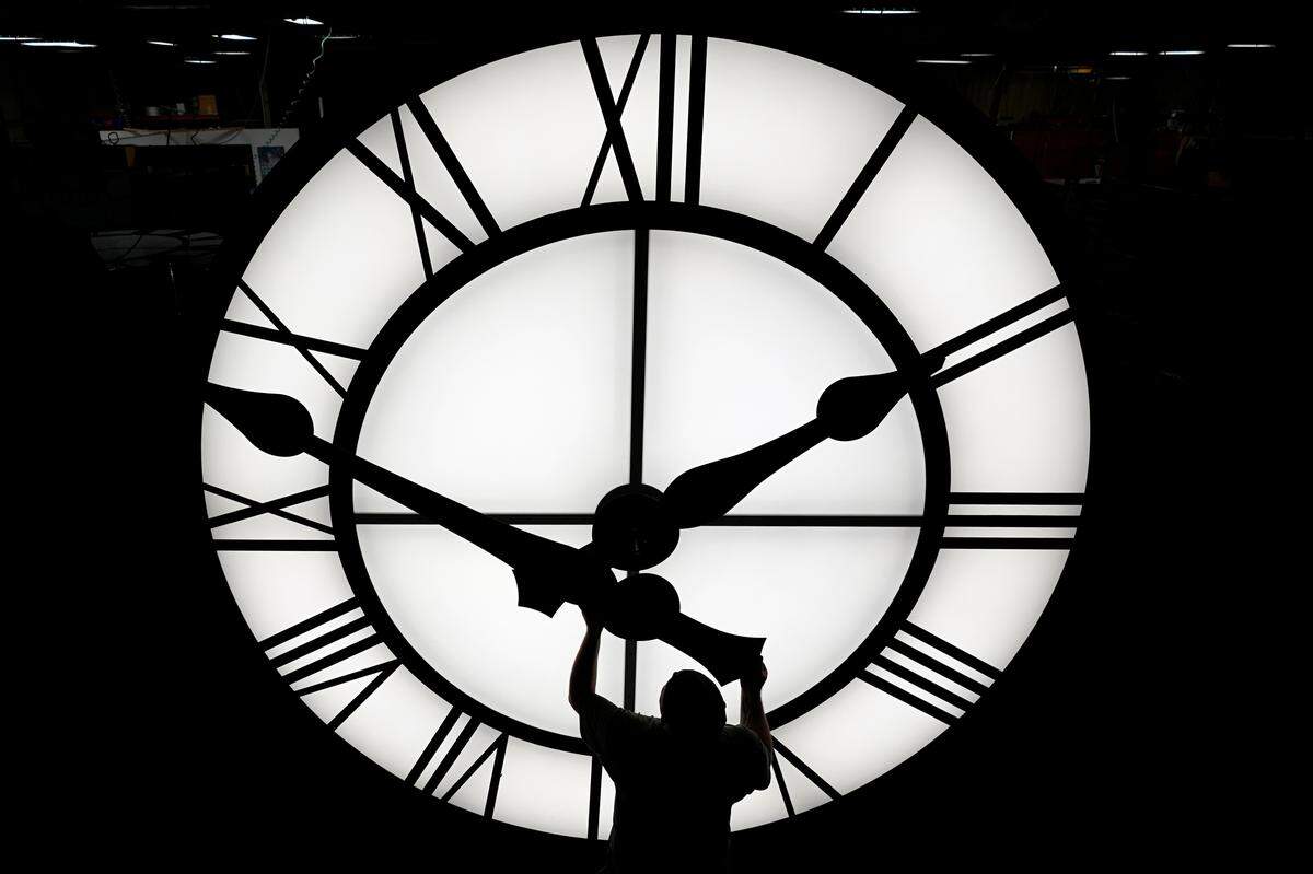 FILE - Electric Time technician Dan LaMoore puts a clock hand onto a 1000-lb., 12-foot diameter clock constructed for a resort in Vietnam, Tuesday, March 9, 2021, in Medfield, Mass. AP Photo/Elise Amendola, File)