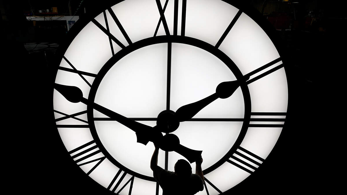 FILE - Electric Time technician Dan LaMoore puts a clock hand onto a 1000-lb., 12-foot diameter clock constructed for a resort in Vietnam, Tuesday, March 9, 2021, in Medfield, Mass. AP Photo/Elise Amendola, File)