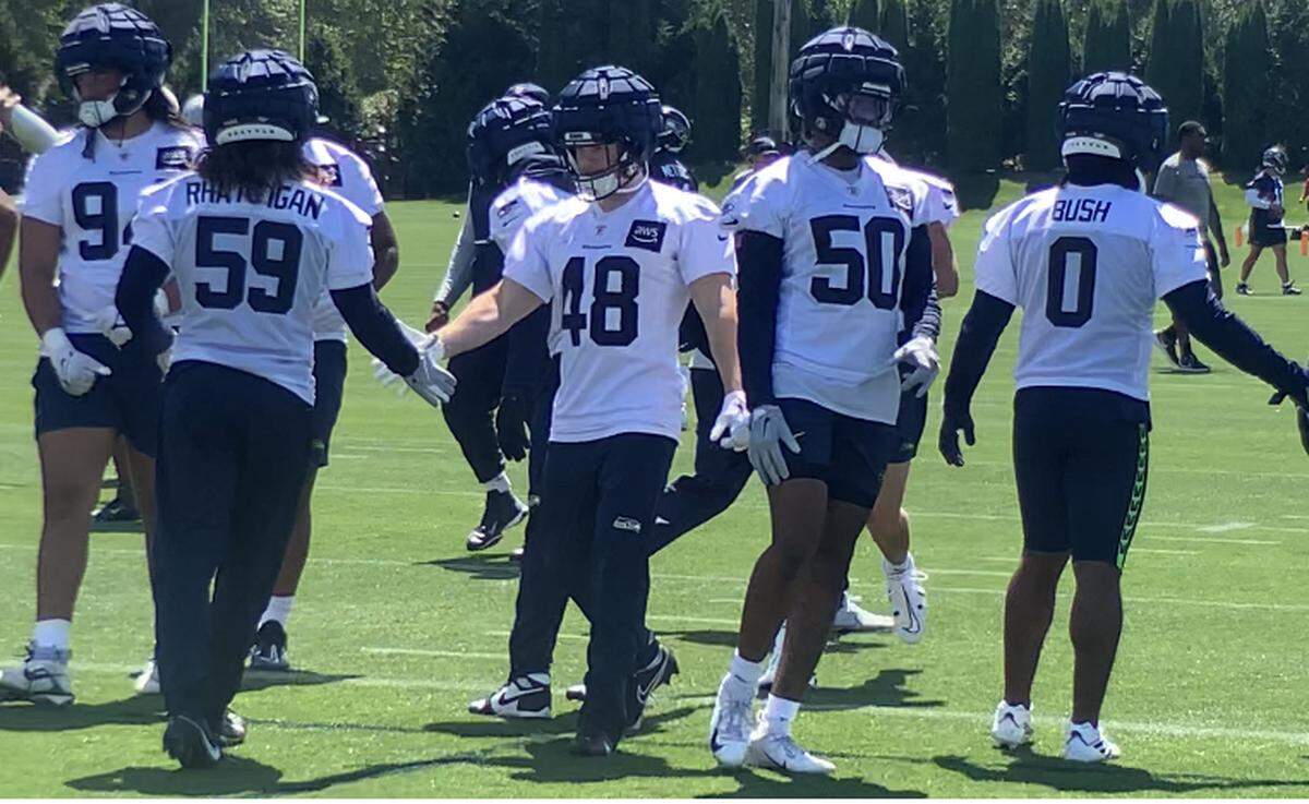 Linebacker and special-teams veteran Ben Burr-Kirven (48) slaps hands with fellow linebacker Jon Rhattigan (59) at the start of practice at Seahawks training camp in Renton July 27, 2023. It was Burr-Kirven’s first practice in two years, following surgery and nerve damage in his leg. He signed back with the team on July 27, 2023, one day after a tryout.