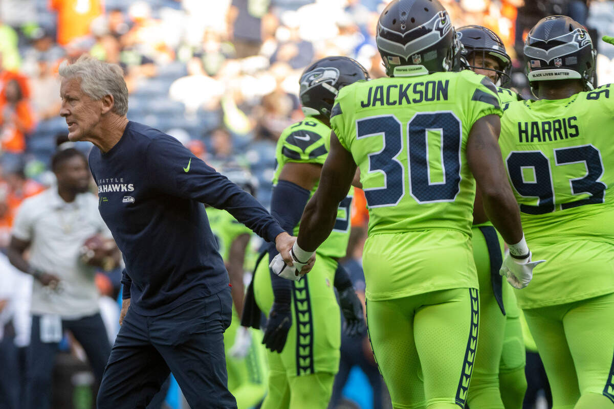 Seattle Seahawks head coach Pete Carroll shakes hands with Seattle Seahawks cornerback Michael Jackson (30) during warm ups prior to the start of an NFL game against the Denver Broncos on Monday, Sept. 12, 2022, at Lumen Field in Seattle.