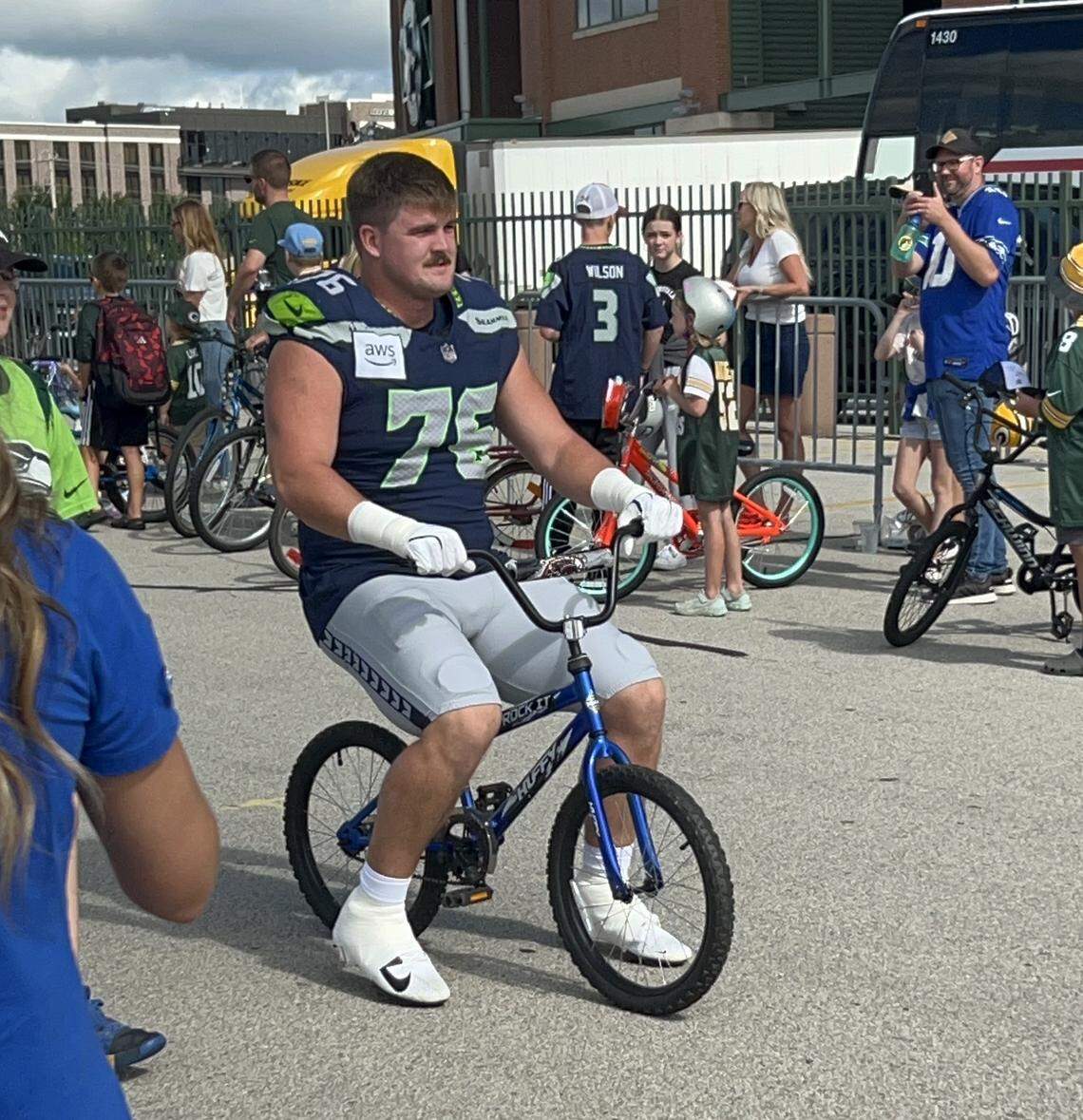 Seahawks rookie guard Grey Zabel uses a local boy’s small bike with no hand brakes to go from the locker room at Lambeau Field to the NFL preseason joint practice Seattle had with the Packers in Green Bay, Wisconsin, Thursday, Aug. 21, 2025.
