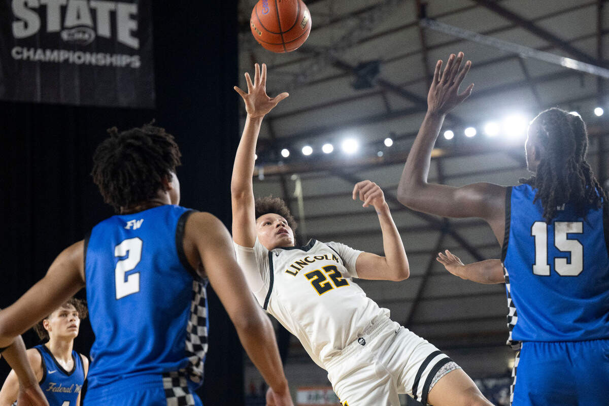 Lincoln’s Justus Holt (22) attempts an off-balance shot over a pair of Federal Way defenders during the second half of a Class 3A state basketball tournament first-round game at the Tacoma Dome on Wednesday, March 5, 2025, in Tacoma, Wash.