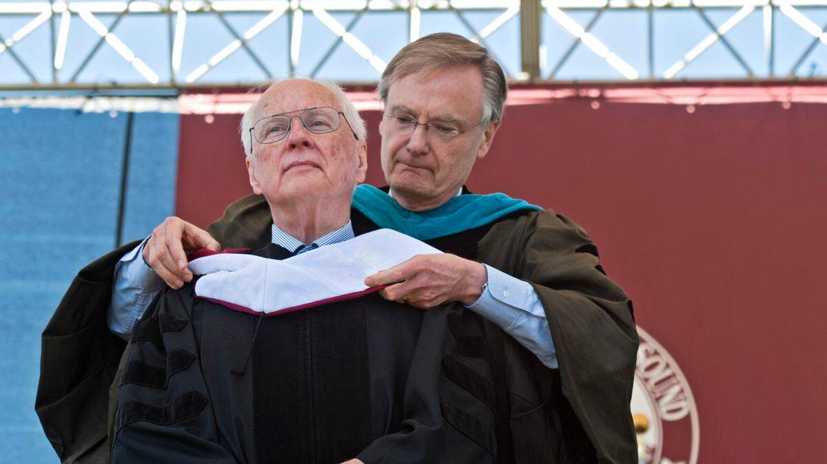 A hood is placed over the head of Dennis Flannigan, who received an honorary degree in the commencement ceremony at University of Puget Sound in Tacoma, May 13, 2012. Placing the hood is Bill Baarsma, professor emeritus of Business and Public Administration and former Tacoma mayor.