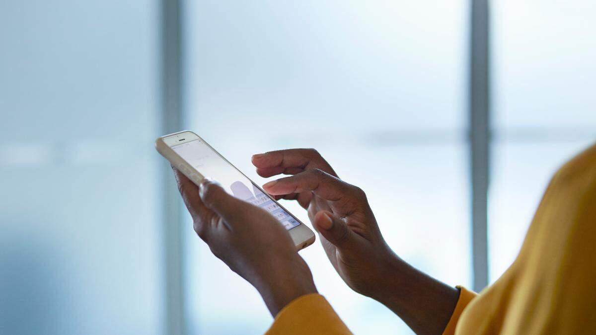 Close-up of businesswomans hands holding phone, in conference room