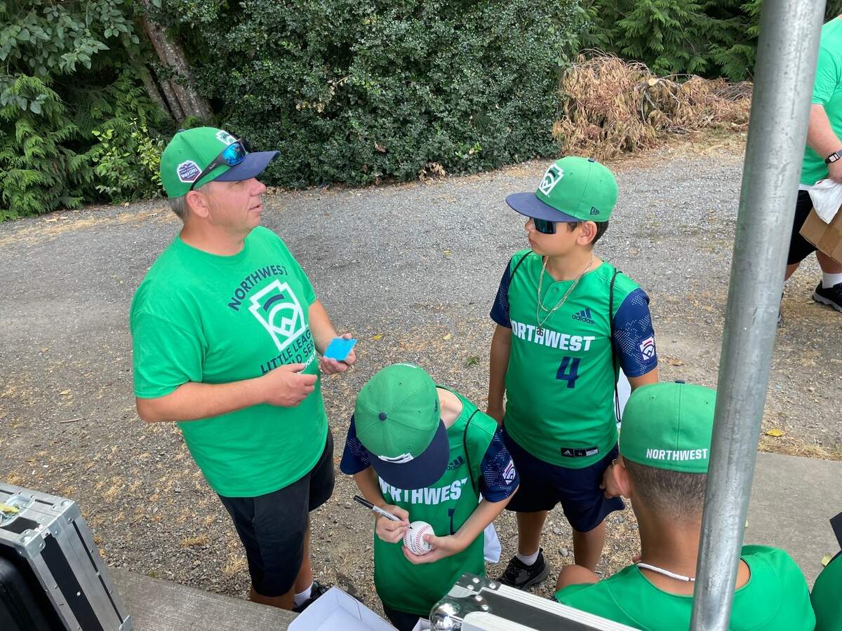 12-year-old Ezra Seitz signs a baseball in his Northwest uniform. Seitz was part of the Bonney Lake-Sumner 12-and-under all star team that made the Little League World Series.