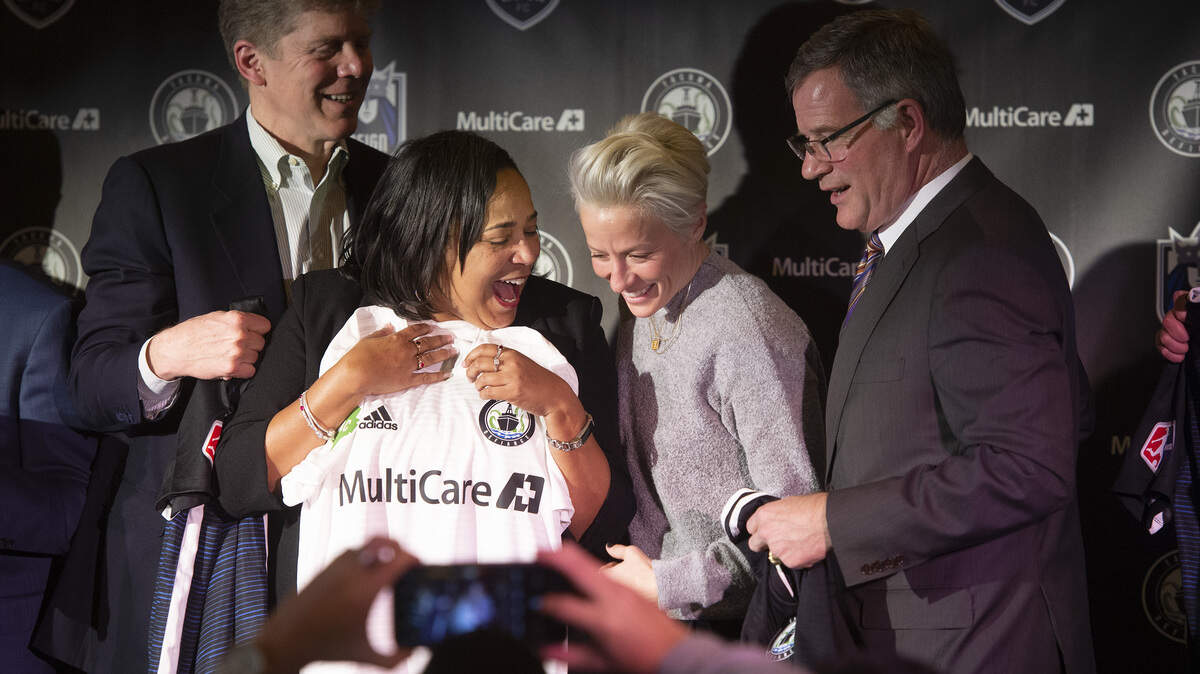 Tacoma mayor Victoria Woodards and Seattle Reign FC captain Megan Rupinoe celebrate following the announcement that the team will move to Tacoma - and be renamed simply Reign FC - during a press conference at Cheney Stadium in Tacoma on Wednesday, Jan. 30, 2019. Flanking them are Tacoma Rainiers owner Mikal Thompson, left, and Pierce County Executive Bruce Dammeier, right.