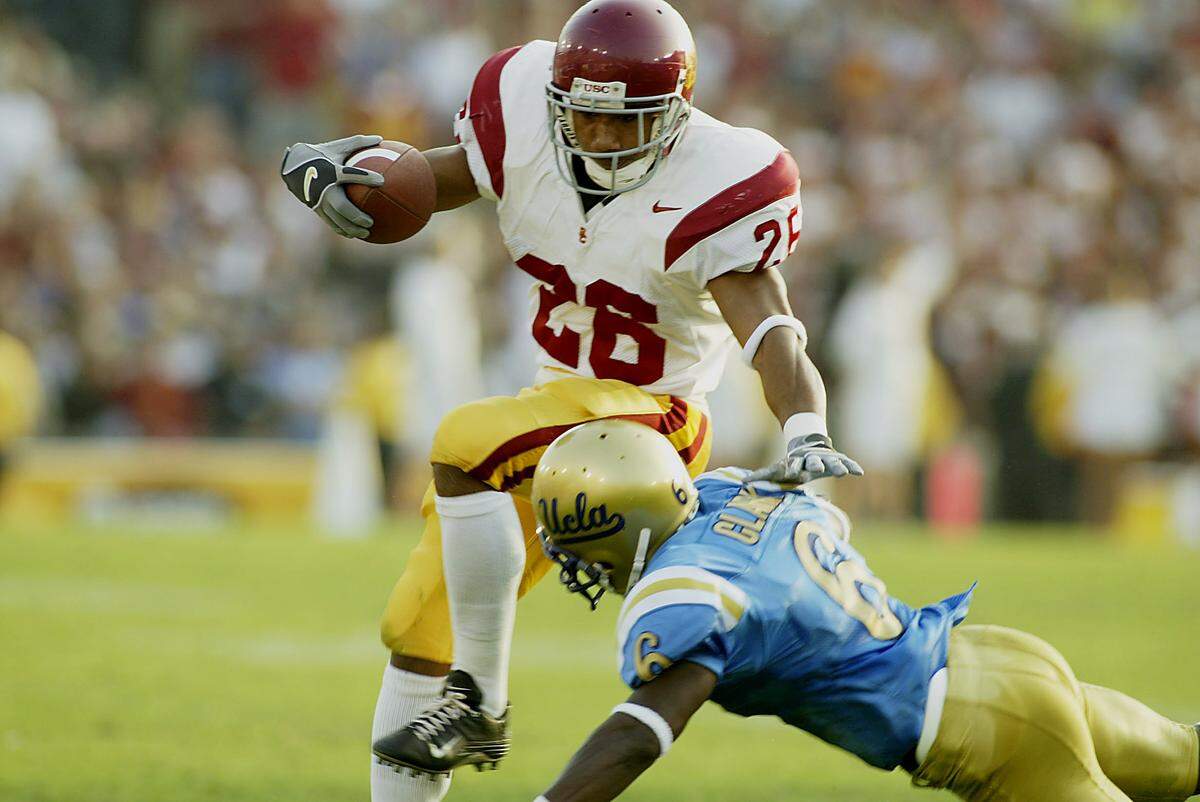 PASADENA, CA - NOVEMBER 23: Hershel Dennis #26 of USC tries to avoid Matt Clark #6 of UCLA during the second half on November 23, 2002 at the Rose Bowl in Pasadena, California. USC beat UCLA 52-21. (Photo By Christopher Ruppel/Getty Images)