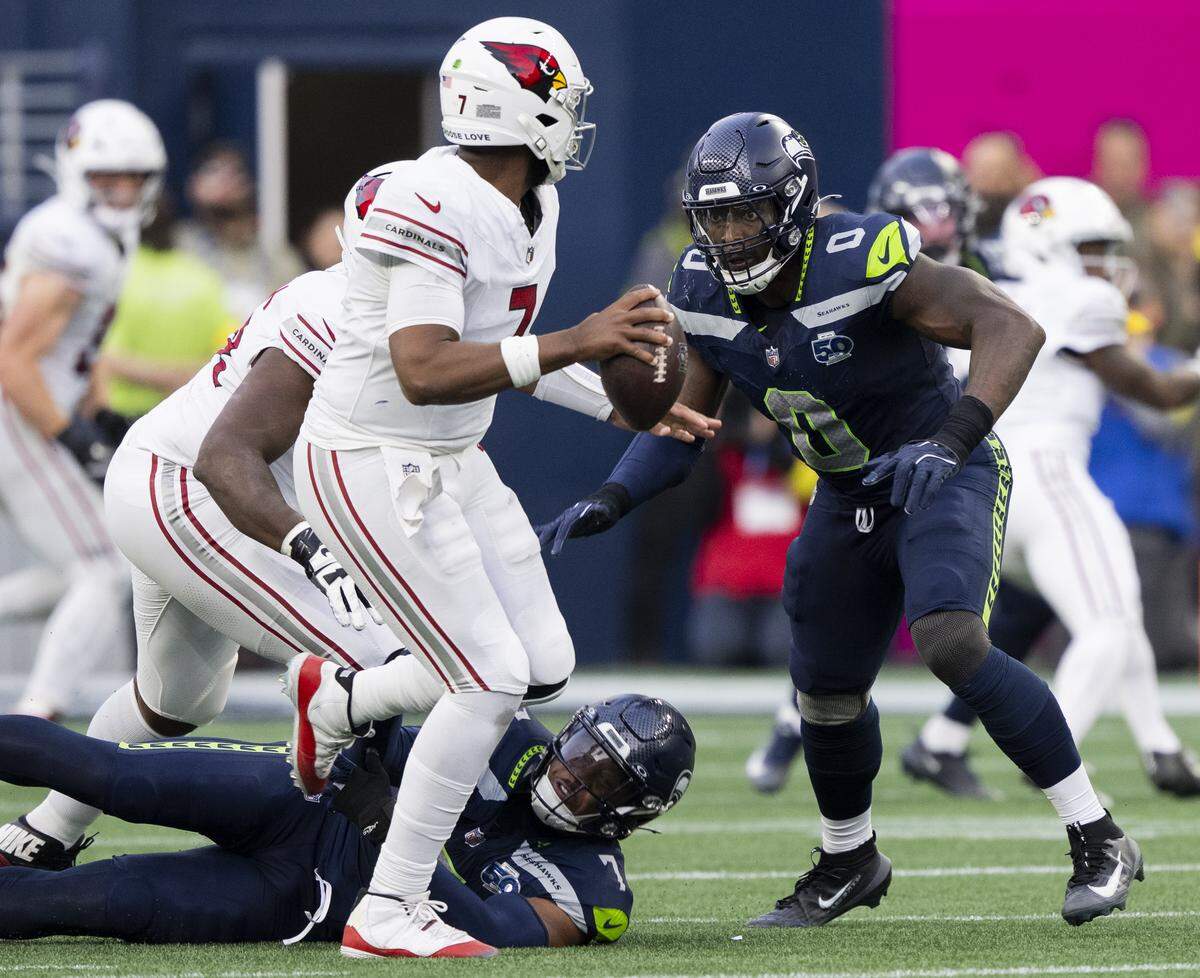 Seattle Seahawks defensive end DeMarcus Lawrence (0) and linebacker Uchenna Nwosu (7) pressure Arizona Cardinals quarterback Jacoby Brissett (7) during the fourth quarter of the game at Lumen Field, on Sunday, Nov. 9, 2025, in Seattle.