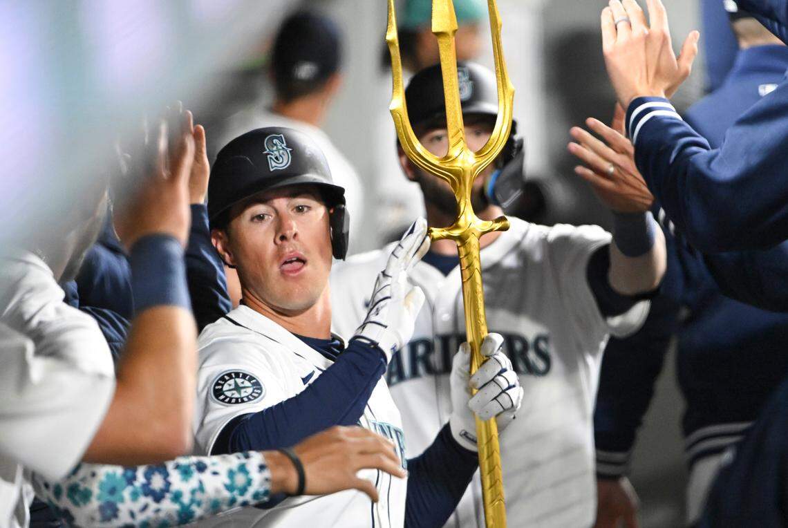 Seattle Mariners left fielder Dylan Moore (25) celebrates a two-run homer against the Boston Red Sox with the trident in the dugout during the seventh inning of the opening day game at T-Mobile Park, on Thursday, March 28, 2024, in Seattle, Wash.