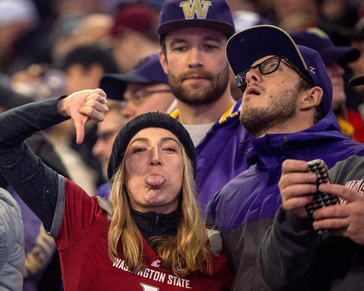 A Washington State fan gives the thumbs down while standing next to a Washington fan during the 2021 Apple Cup on Friday at Husky Stadium in Seattle.