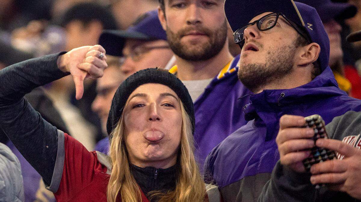 A Washington State fan gives the thumbs down while standing next to a Washington fan during the 2021 Apple Cup on Friday at Husky Stadium in Seattle.