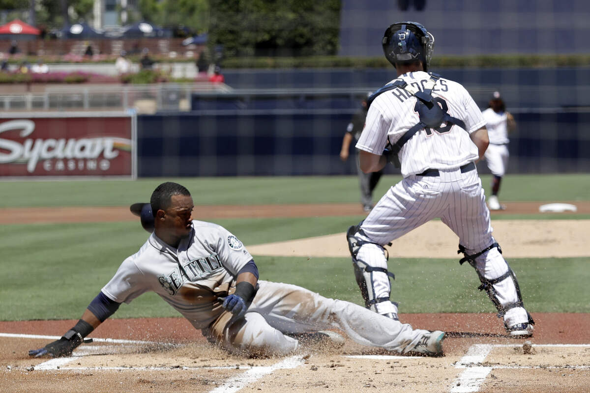 Seattle Mariners’ Jean Segura, below, slides in safely to score off an RBI single by Robinson Cano as San Diego Padres catcher Austin Hedges waits for the throw during the first inning of a baseball game Wednesday, Aug. 29, 2018, in San Diego. (AP Photo/Gregory Bull)