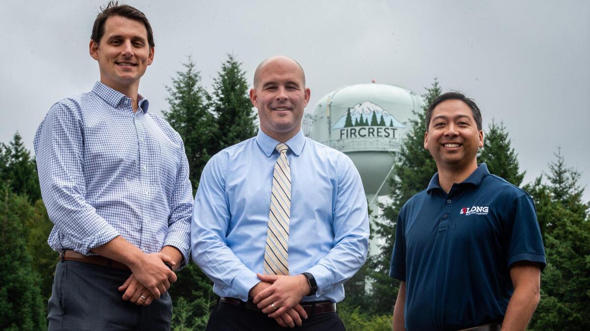 From left: Fircrest resident Andrew Imholt, city manger Scott Pingel, and Charles Pham, with Long Painting Company, stand for a portrait with the newly-painted Fircrest water tower in Fircrest, Wash., on Monday, July 15, 2019. The water tower is now adorned with a mural depicting Fircrest’s logo. According to residents, it helps give citizens pride in their small city.