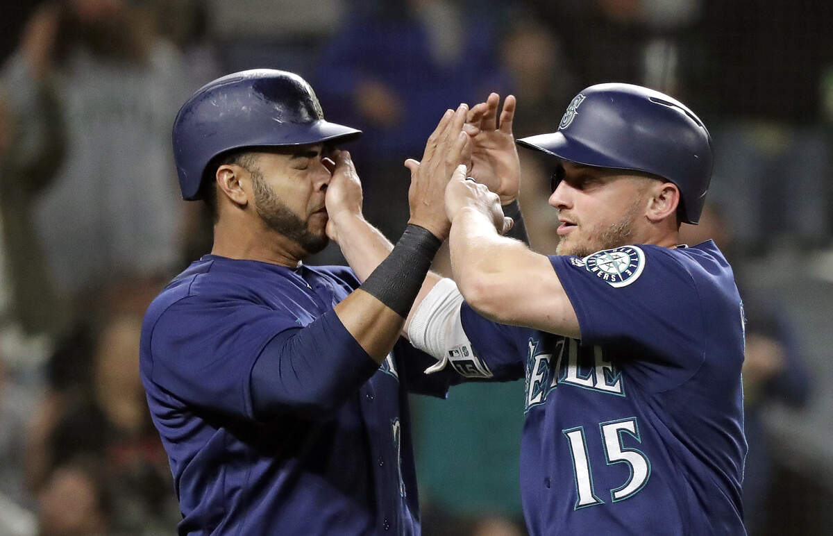 Seattle Mariners' Kyle Seager (15) misses on one of his high-fives as he celebrates with Nelson Cruz after scoring against the Detroit Tigers during the seventh inning of a baseball game Friday, May 18, 2018, in Seattle. (AP Photo/Elaine Thompson)