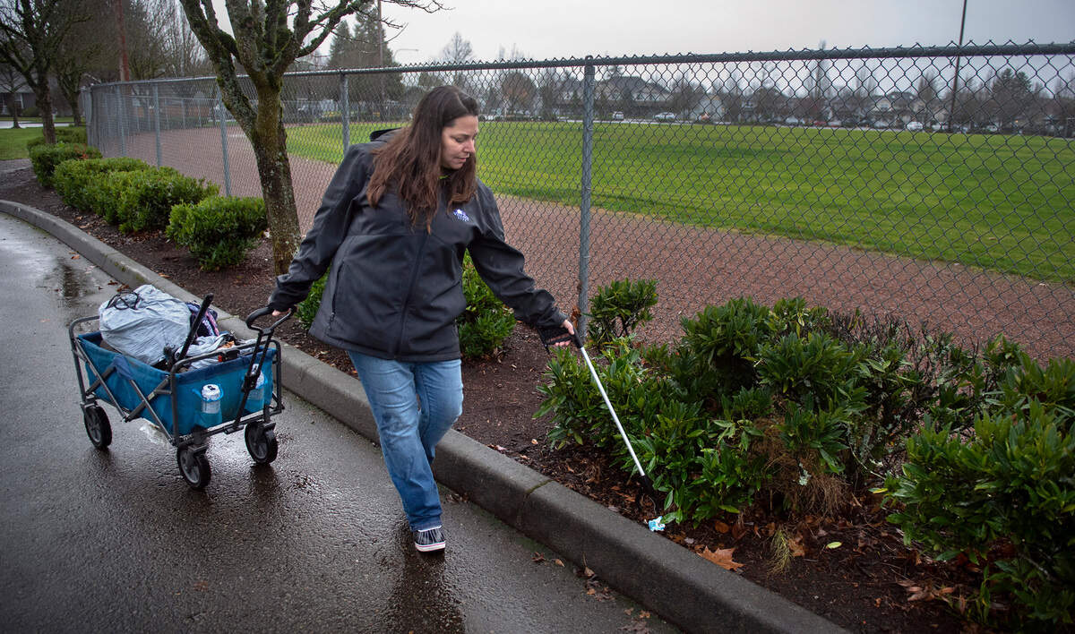 Katlin Lawless, founder of the unofficial “Sumner Cleaning Crew” that now boasts more than 100 members, picks up trash on her walk around Daffodil Valley Athletic Complex in Sumner, Washington, on Saturday, Dec. 11, 2021.