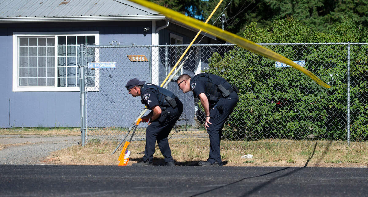 Officers with the Pierce County Sheriff’s Department scan Ainsworth Ave. S. for tire tracks to mark as roadway evidence Saturday, July 24, 2021. Detectives are investigating a homicide after one man deliberately ran over another man in Parkland.