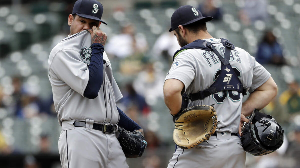 Seattle Mariners starting pitcher Felix Hernandez, left, gets a visit to the mound by catcher David Freitas after Hernandez gave up a two-run double to Oakland Athletics’ Stephen Piscotty in the first inning of a baseball game, Thursday, May 24, 2018, in Oakland, Calif. (AP Photo/Marcio Jose Sanchez)