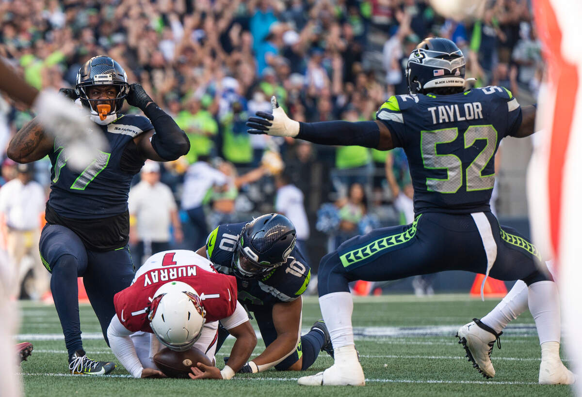Seattle Seahawks defensive tackle Quinton Jefferson (77) and Seattle Seahawks defensive end Darrell Taylor (52) celebrate after Jefferson and Seattle Seahawks linebacker Uchenna Nwosu (10) sack Arizona Cardinals quarterback Kyler Murray (1) in the fourth quarter of an NFL game on Sunday, Oct. 16, 2022, at Lumen Field in Seattle.