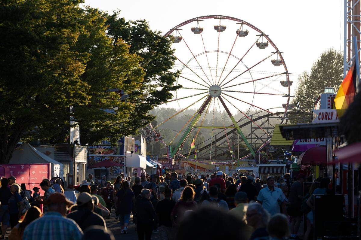 Farigoers line the midway as the Grand Wheel spins during the opening day of the Washington State Fair, on Friday, Aug. 30, 2024, in Puyallup, Wash.
