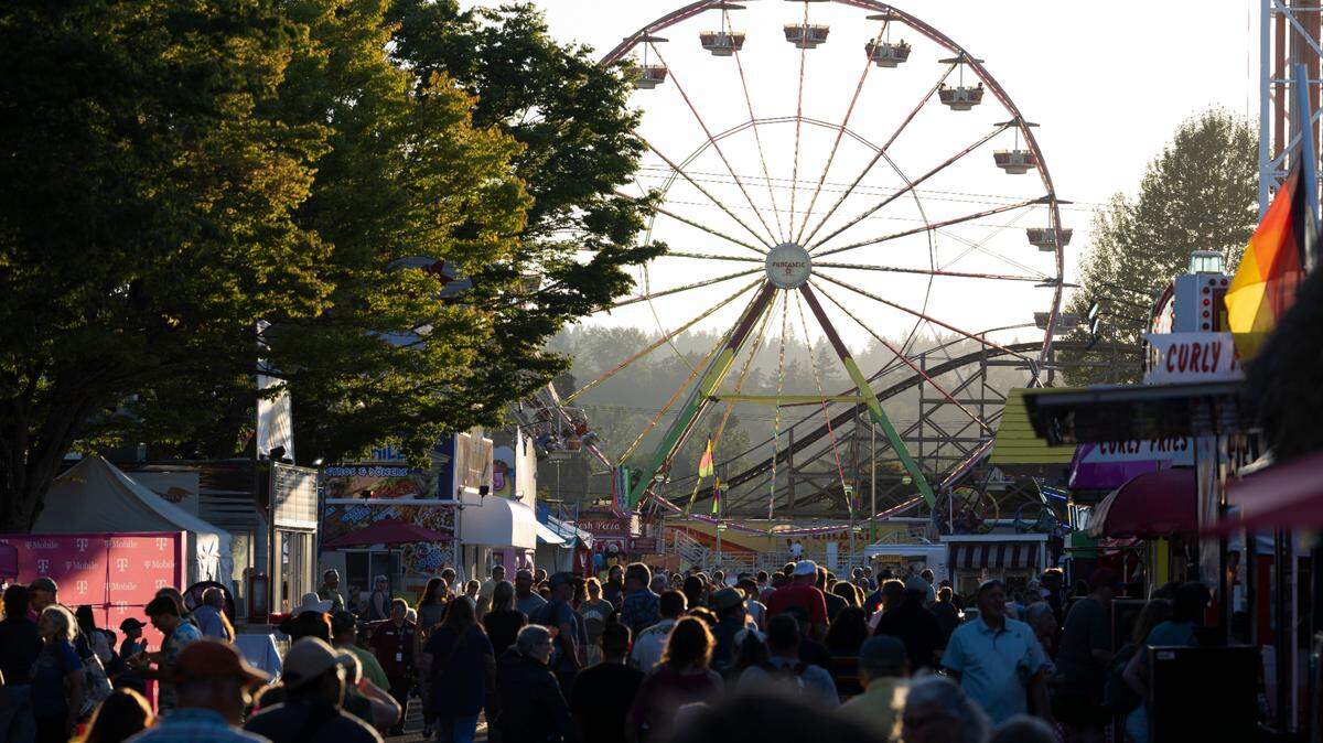 Fairgoers line the midway as the Grand Wheel spins during the opening day of the 2024 Washington State Fair in Puyallup.