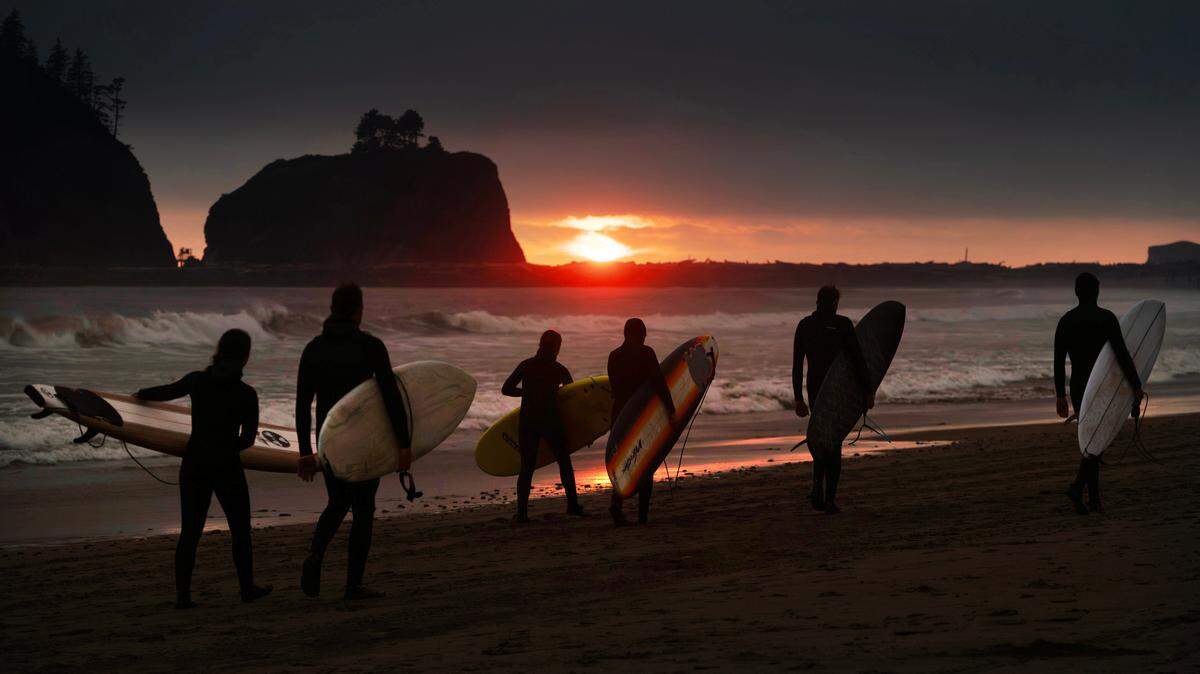 Surfers walk back to camp at sunset along First Beach in LaPush, Washington, on Saturday, July 20, 2024.