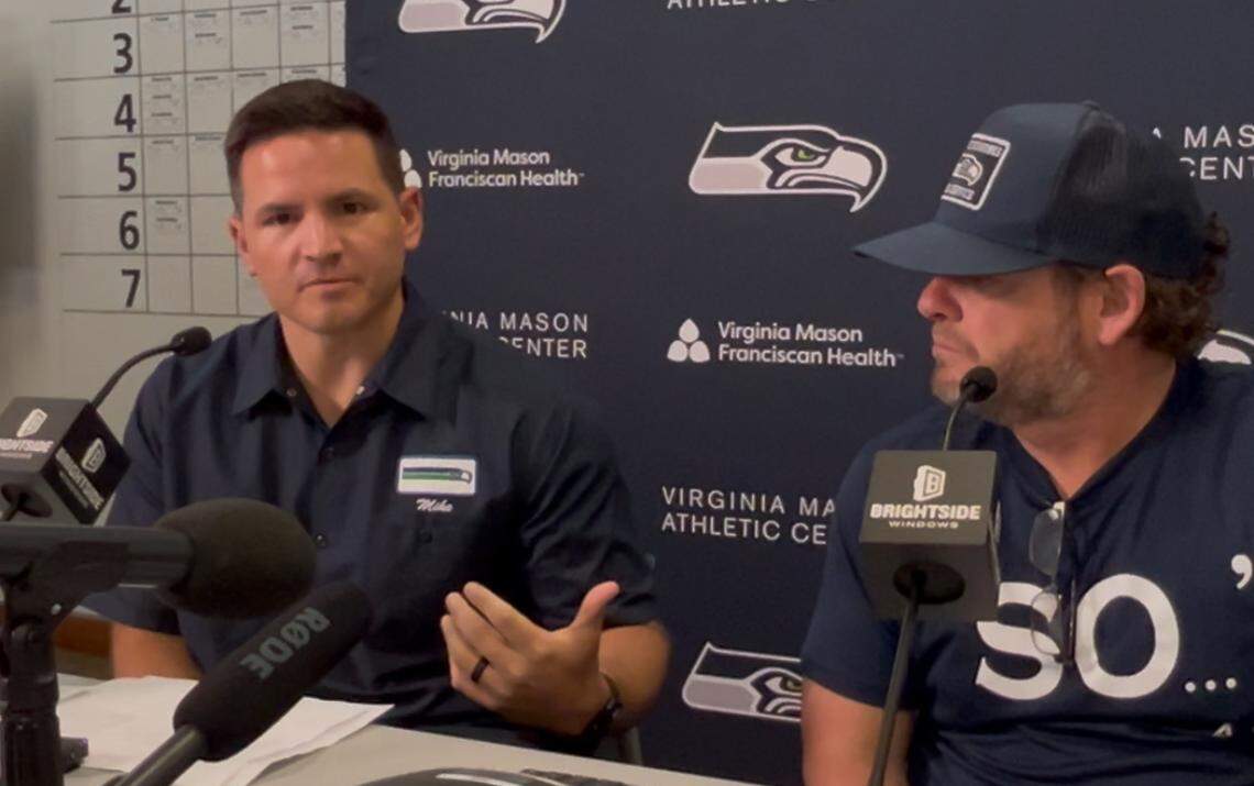 Seahawks coach Mike Macdonald (left), wearing the gas-station attendant shirt the team’s decision-makers often wear around team headquarters, discusses the NFL draft at its end April 26, 2025. General manager John Schneider (right) is listening.
