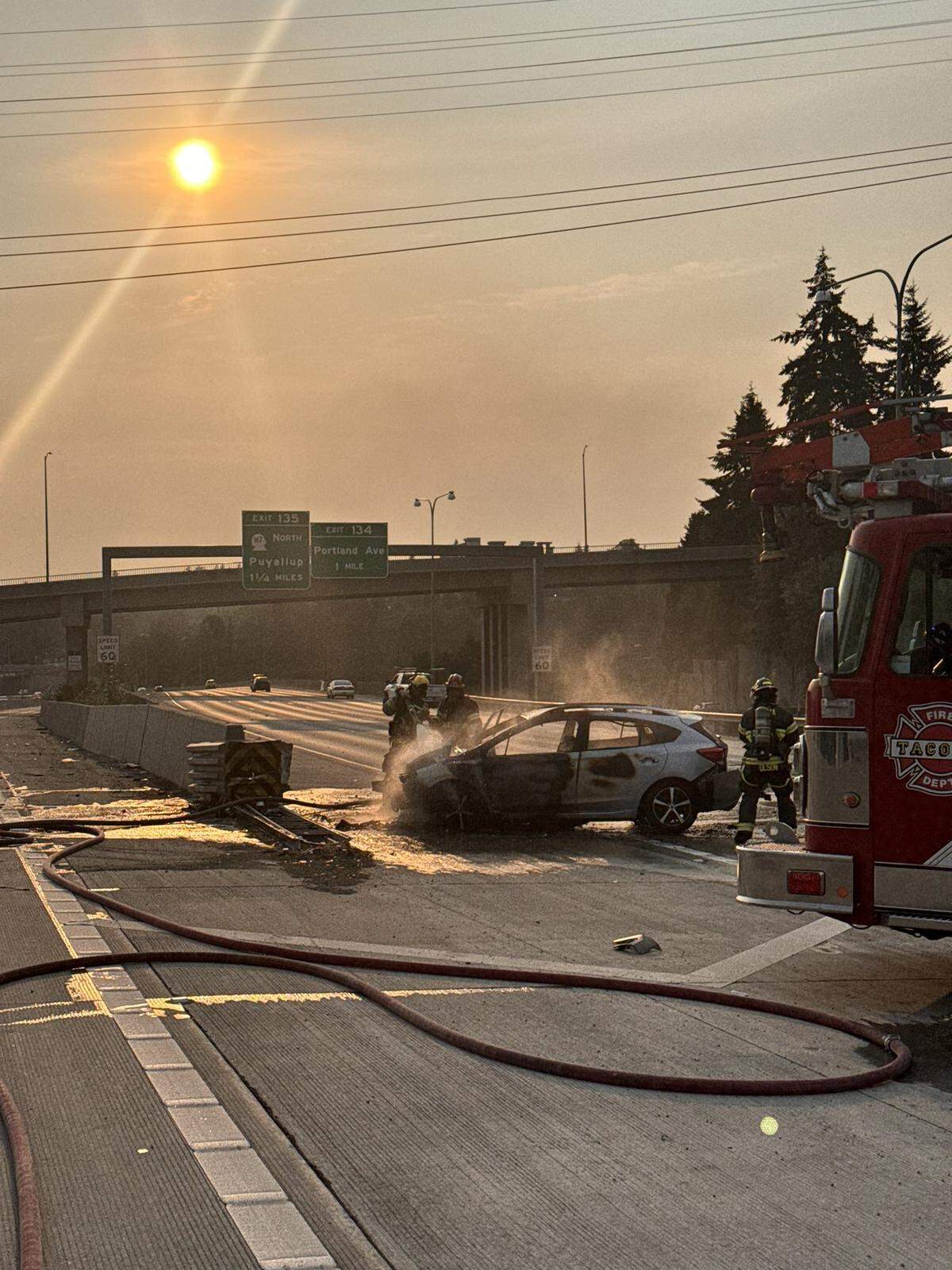 A car burst into flames on I-5 near the Tacoma Dome after it struck a barrier.
