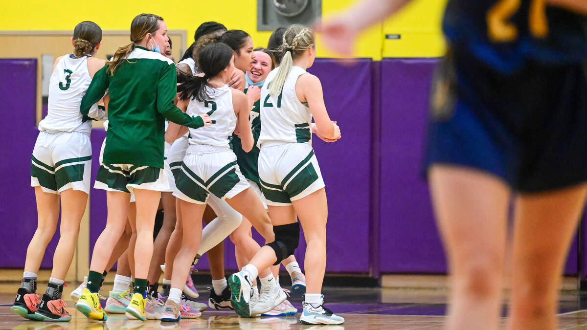 Auburn players congratulate guard Madelyn Brown (23) after her three-quarters of the court buzzer beater at the end of the second quarter of a Class 3A state regional play-in game against West Seattle on Friday, Feb. 25, 2022, at Puyallup High School in Puyallup, Wash.