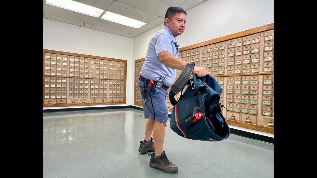 Letter carrier Siegfried Malang demonstrates how to use a satchel to defend against an attacking dog.