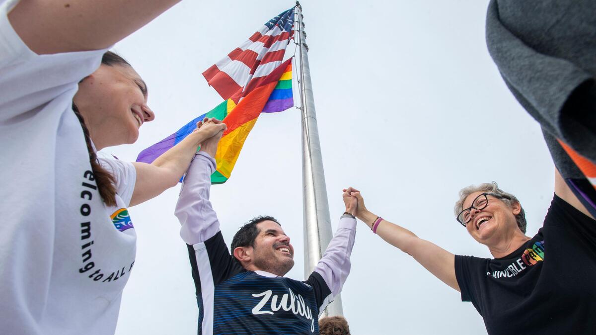 Puyallup Tribal Council member Annette Bryan, left, then-Tacoma City Council member Ryan Mello, and state Rep. Laurie Jinkins celebrate after the first-ever raising of the iconic rainbow gay pride flag over the Tacoma Dome on Tuesday, July 9, 2019.