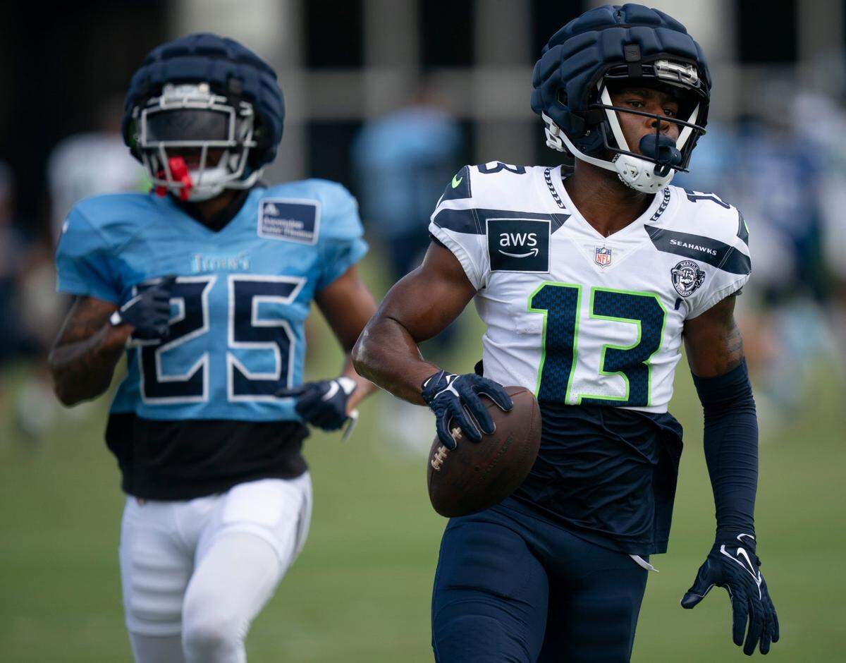 Seattle Seahawks wide receiver Easop Winston Jr. (13) runs after the catch when he beat Tennessee Titans running back Hassan Haskins (25) on the play at Ascension Saint Thomas Sports Park in Nashville, Tenn., Wednesday, Aug. 14 2024. This is the first day of the Titans joint practice with the Seattle Seahawks.
