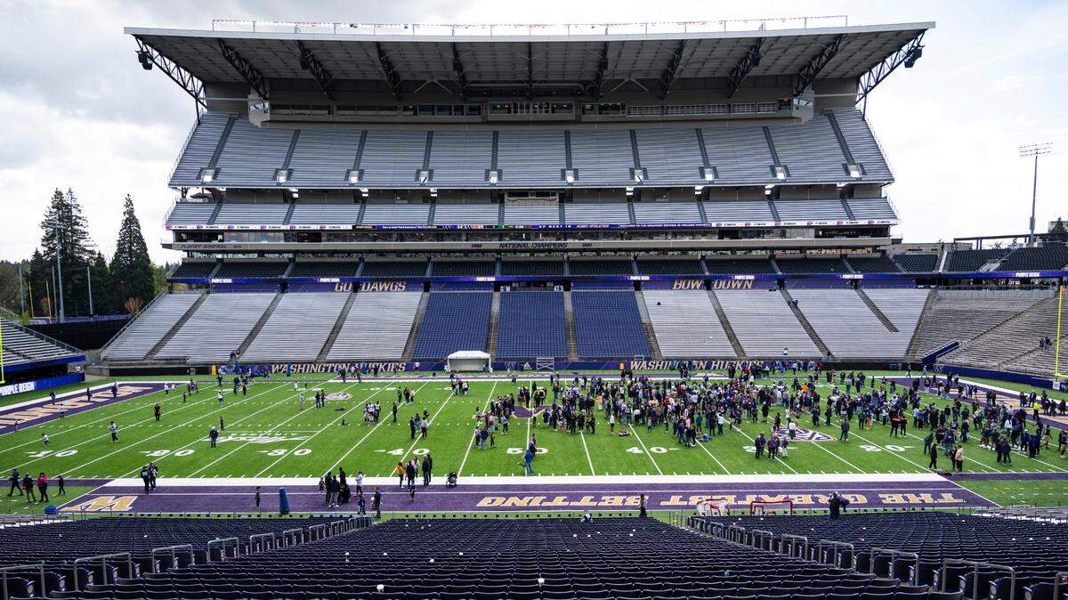 University of Washington Huskies fans and players gather on the field after the spring game at Husky Stadium in Seattle on April 30, 2022.