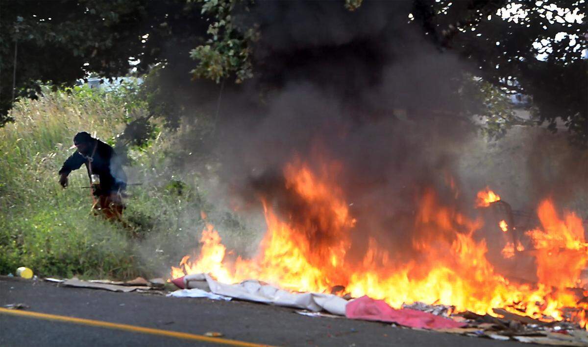 A man runs from a fire at his homeless campsite along the 84th Street offramp onto Hosmer Street in Tacoma, Washington on June 22, 2022.
