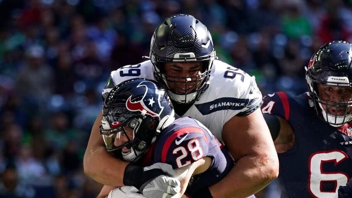 Houston Texans running back Rex Burkhead (28) is stopped by Seattle Seahawks defensive tackle Al Woods (99) during the first half of an NFL football game, Sunday, Dec. 12, 2021, in Houston. (AP Photo/Eric Christian Smith)