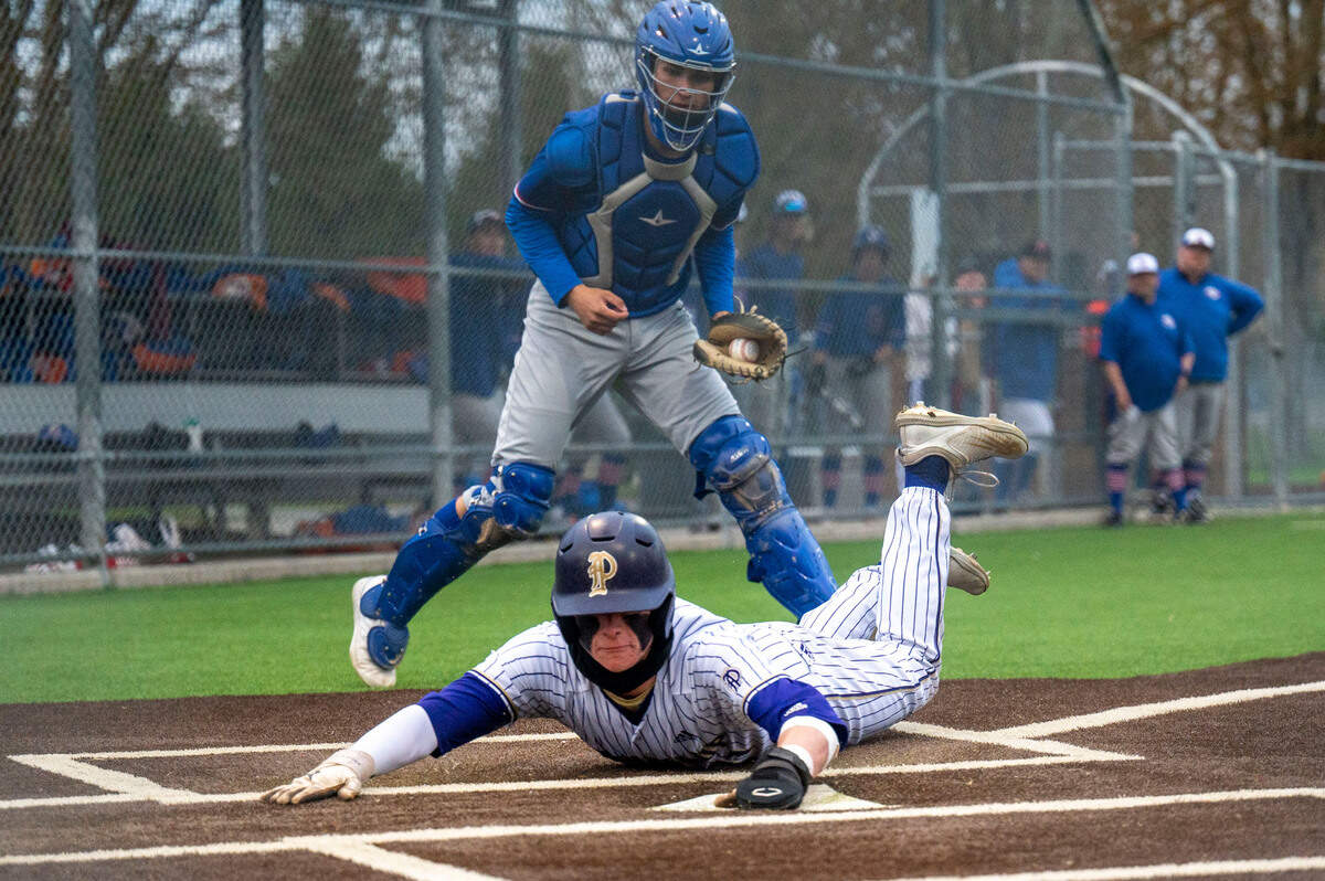 Puyallup’s Garrett Ringer slides safely through home plate as Graham-Kapowsin catcher Brandon Kim looks on after chasing down a wild pitch during a 4A South Puget Sound League game on Tuesday, May 3, 2022, at Heritage Park in Puyallup.