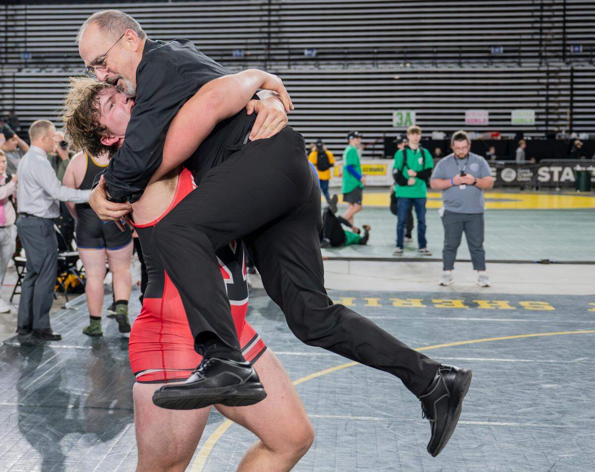 Yelm’s Jonah Smith hugs head coach Gaylord Strand after winning the 285-pound 3A championship during day two of the Mat Classic XXXV at the Tacoma Dome on Saturday, Feb. 17, 2024, in Tacoma, Washington. Coach Strand is retiring and this was his last match coaching.
