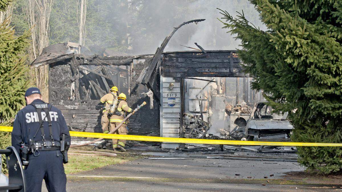 A Pierce County Sheriff’s deputy and Graham Firefighters work around the smoldering remains of a house near Fredrickson where, according to a sheriff’s spokesman, three bodies were were found, February 5, 2012. They are believed to be Josh Powell and his two children. Fire accelerant is believed to be involved in the apparent murder-suicide. A Child Protective Services worker had been supervising a visit and is safe but traumatized. (Pool photo by Peter Haley / The News Tribune, via AP)