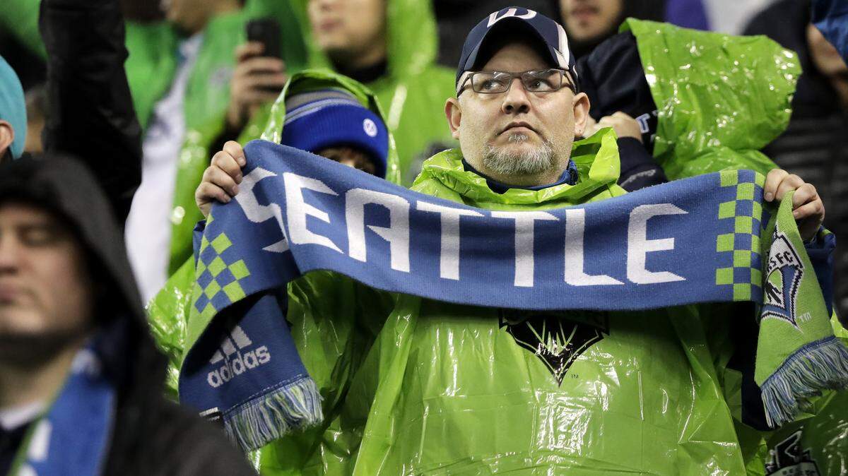 A Seattle Sounders supporter holds a scarf as he stands in the rain before an MLS soccer match against the Houston Dynamo, Monday, Oct. 8, 2018, in Seattle. (AP Photo/Ted S. Warren)