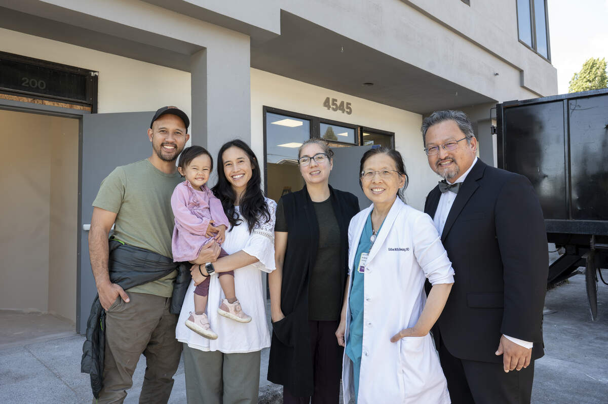 Local health specialists including, from left, Jed De La Paz, a dentist at Bright Smile Dental, daughter Aliana, 2, Alix De La Paz, a life and wellness coach, Elida Jerez, a health director, Esther Park Hwang, OBGYN, and Chan Hwang gather for a photo outside of the future home for the Blessed Hope Health Center on Friday, July 25, 2025, in Tacoma. The two-story building, currently under construction, expects to offer dental, vision, and birth and child care services, as well physical therapy and a pharmacy.