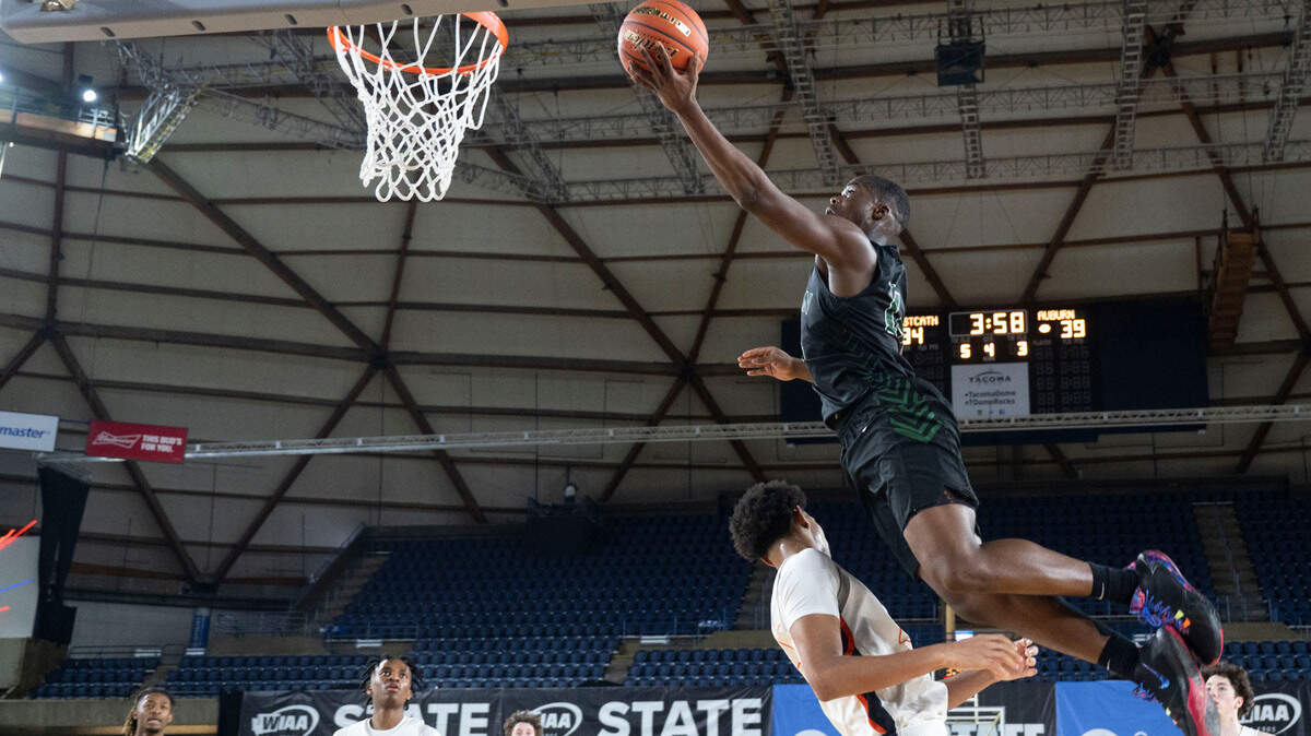 Auburn guard Luvens Valcin (14) dunks the ball over Eastside Catholic forward Jacob Cofie (24) during the fourth quarter of a Class 3A quarterfinal game on Thursday, March 2, 2023, in Tacoma, Wash.