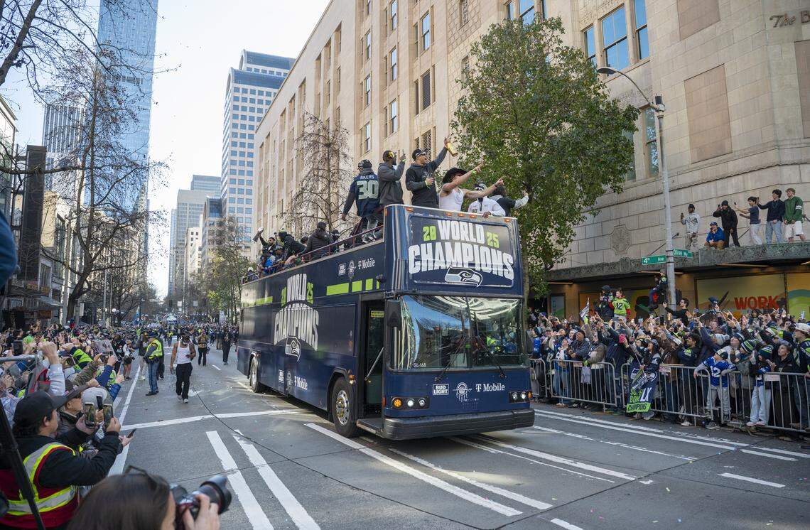 Seahawks players, including running backs Cam Akers and Zach Charbonnet and tight end AJ Barner wave to fans from a bus during the Super Bowl parade on Wednesday, Feb. 11, 2026, in Seattle.
