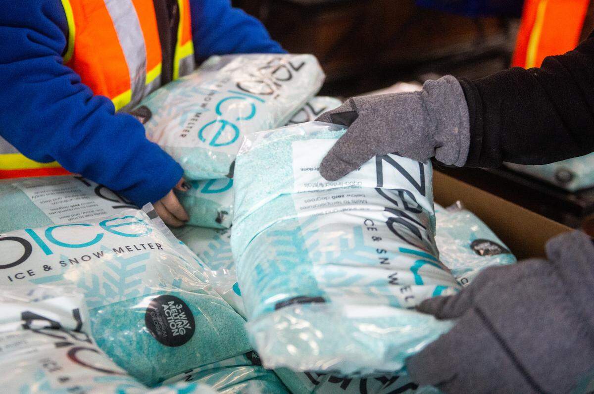 Customers and employees grab bags full of de-icer at McLendon Hardware in Tacoma, Wash., on Friday, Feb. 8, 2019.
