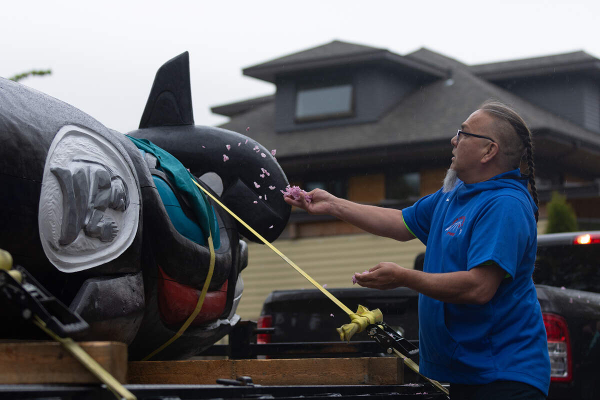 Lummi Tribal member Phreddie Lane uses flowers to bless the totem pole at the The Snake River to Salish Sea Spirit of the Waters totem pole journey launch Tuesday, May 3, at Bellingham Unitarian Fellowship.