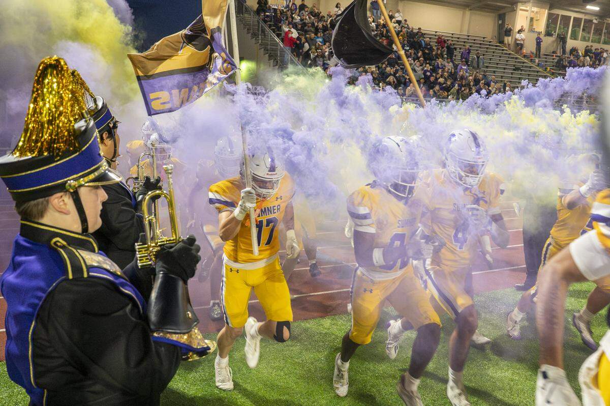 Sumner runs on the field through plumes of purple and yellow smoke before playing against Curtis on Friday, Oct. 17, 2025, in Sumner, Wash.