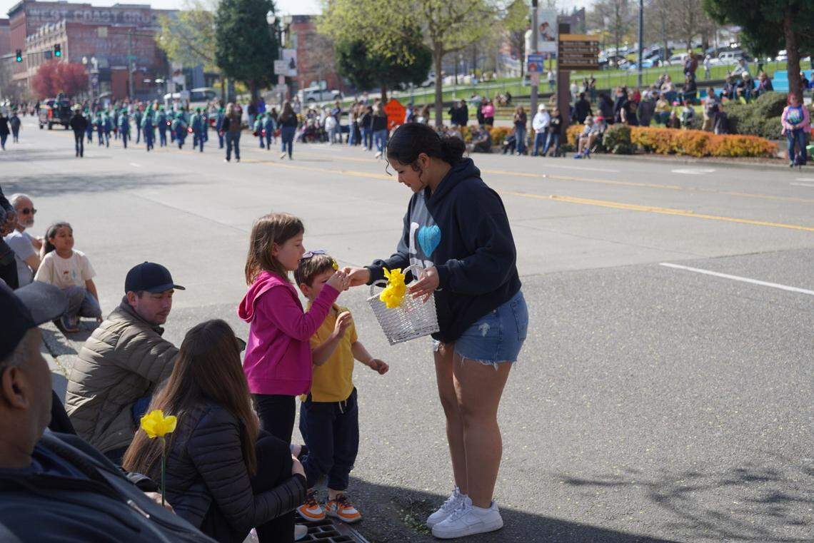 A girl hands out daffodils to parade onlookers as the Bethel Schools float passes by in Tacoma, Wash. on Saturday, April 5, 2025.