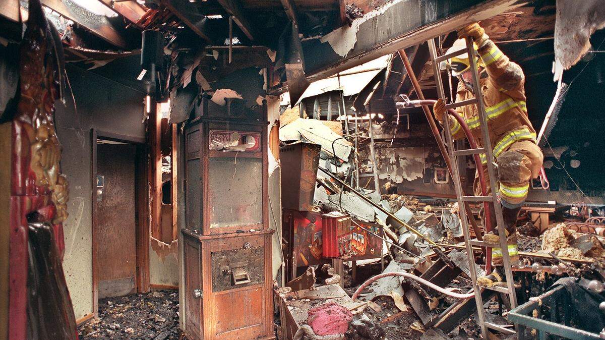 Pierce County Fire District 3, University Place firefighter Robert Dietzway climbs down a ladder after applying water to a smoldering hotspot thirteen hours after popular landmark eatery Pizza & Pipes burned on August 3, 1999.