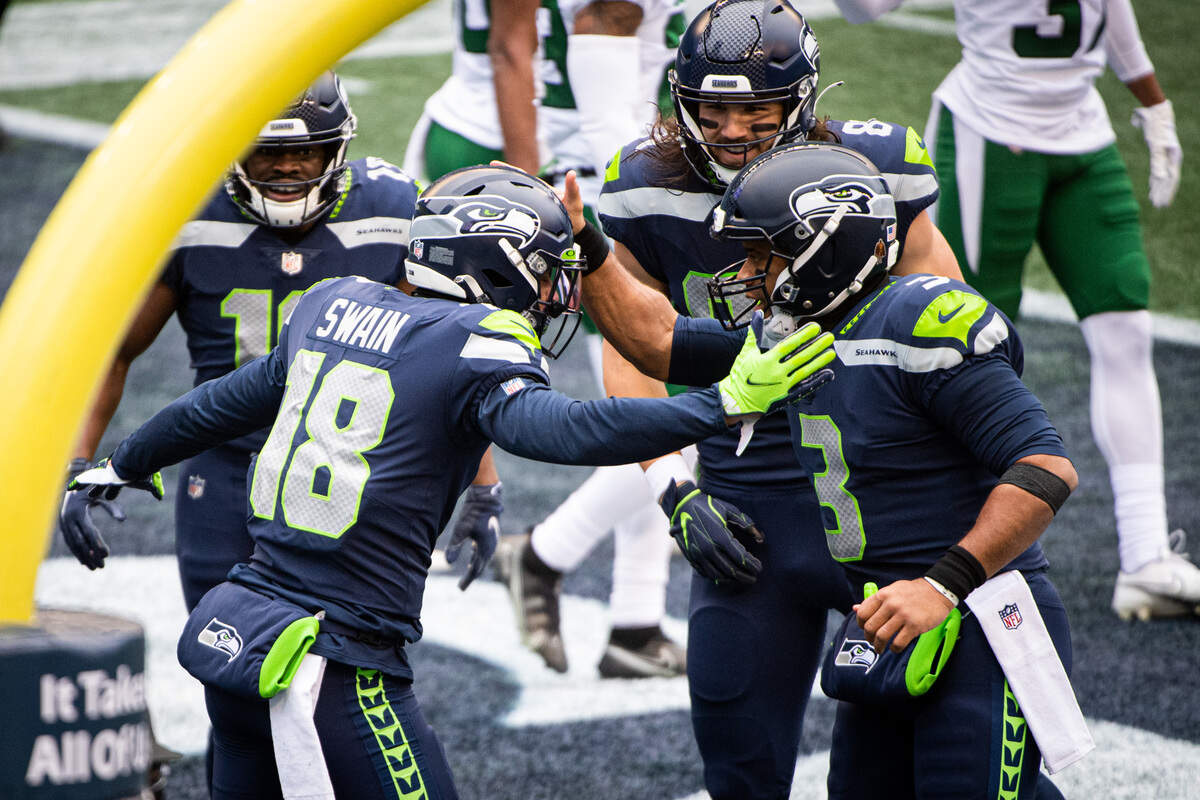 Seattle Seahawks wide receiver Freddie Swain and Seattle Seahawks quarterback Russell Wilson celebrate a touchdown during the first quarter. The Seattle Seahawks played the New York Jets in a NFL football game at Lumen Field in Seattle, Wash., on Sunday, Dec. 13, 2020.