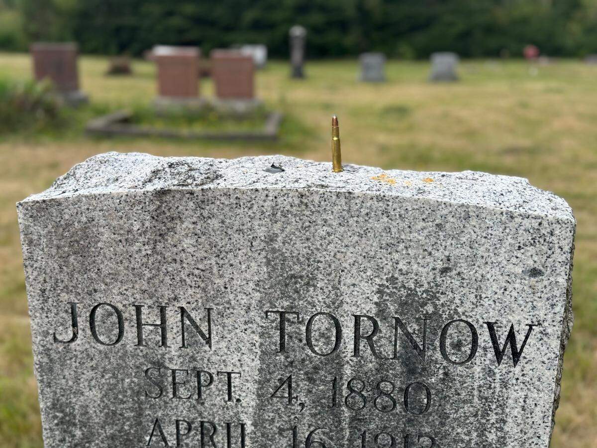 A rifle round rests on the headstone of John Tornow, the Wild Man of the Wynoochee, in the Grove Cemetery near Matlock in August 2024.